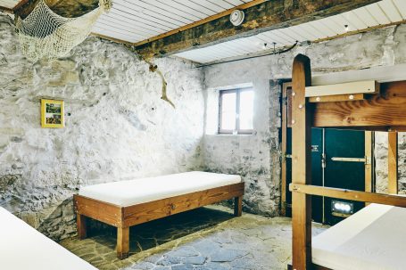 Zimmer mit Steinwänden, Holzbetten und einem Fenster, rustikaler Charme.