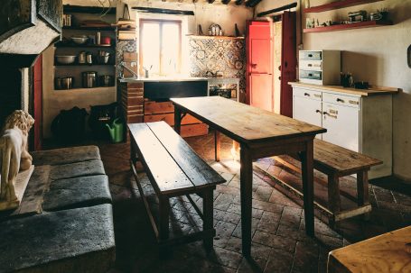 Rustikale Küche mit Holztisch, Bänken und Herd, gemütlicher Atmosphäre.