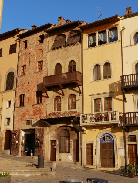 Bunte, historische Gebäude mit Balkonen und Treppen in einer städtischen Landschaft.
