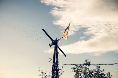 Windrad vor einem sonnigen Himmel und durchziehenden Wolken.