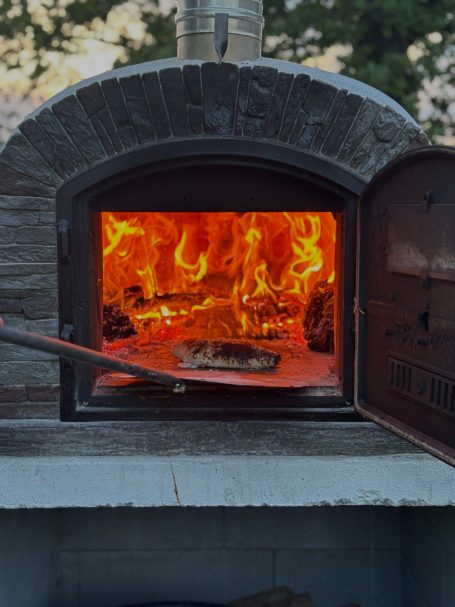 Holzofen mit loderndem Feuer und glühender Glut, bereit zum Backen.