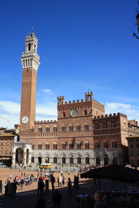 Ein historisches Gebäude mit einem hohen Turm, umgeben von klar blauem Himmel.