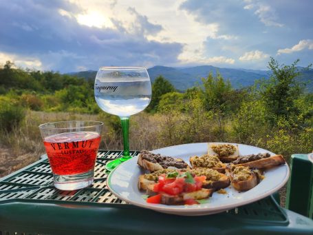 Ein Teller mit Bruschetta und Gläser mit Getränken im Freien.